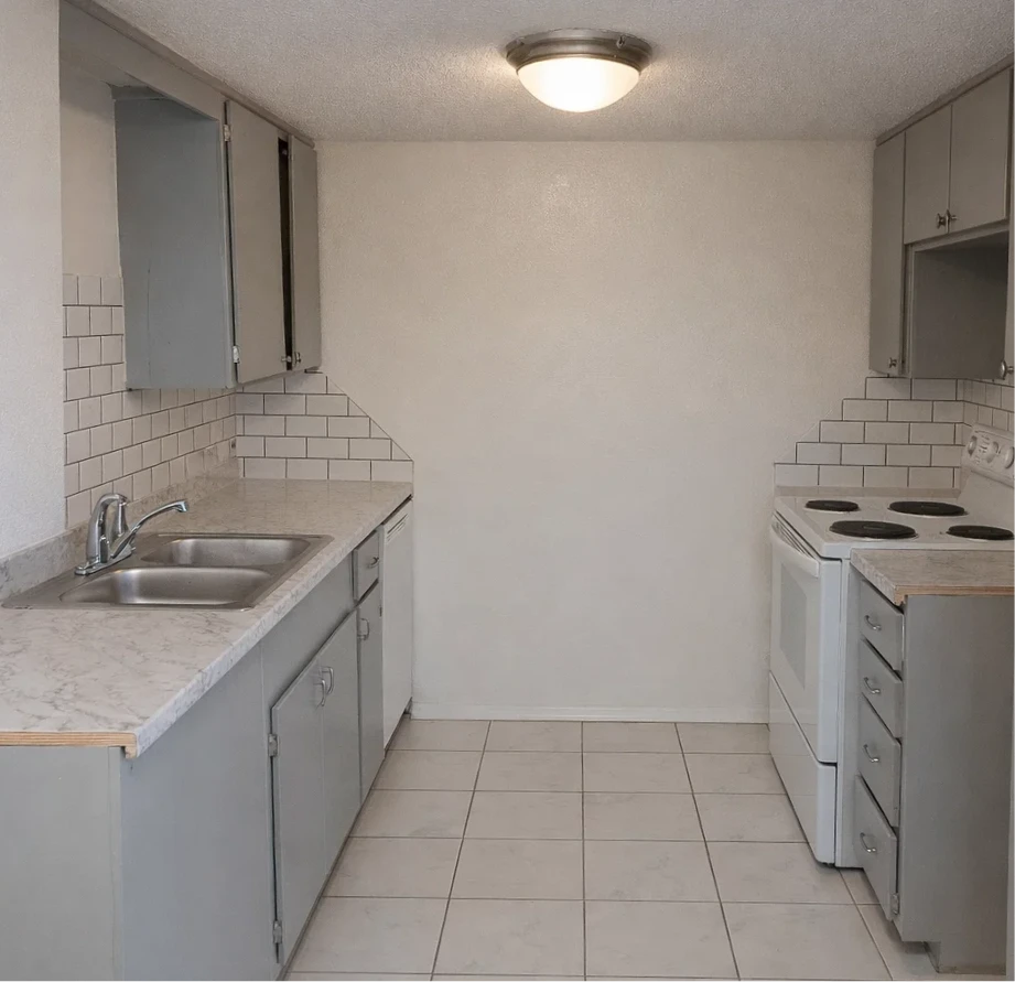 Clean galley-style kitchen with grey cabinets and white appliances in affordable apartments near Oklahoma City.