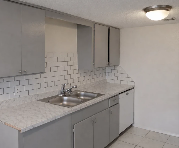 Stainless steel double sink and white dishwasher in utilities included apartments El Reno with grey cabinetry.