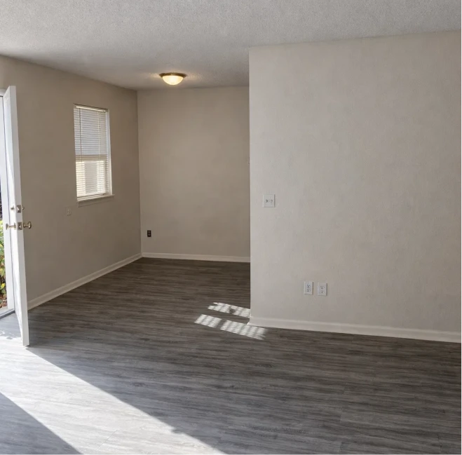 Open living room featuring grey wood-style flooring and natural sunlight in El Reno apartments near Oklahoma City.