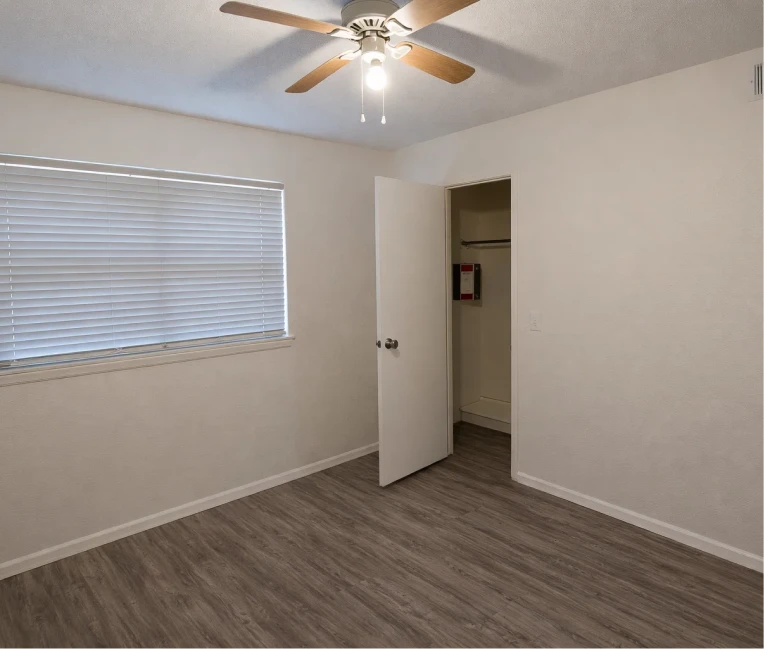 Bright bedroom with wood-style floors and a ceiling fan at La Villa Elms Apartments near I-40 / Route 66.