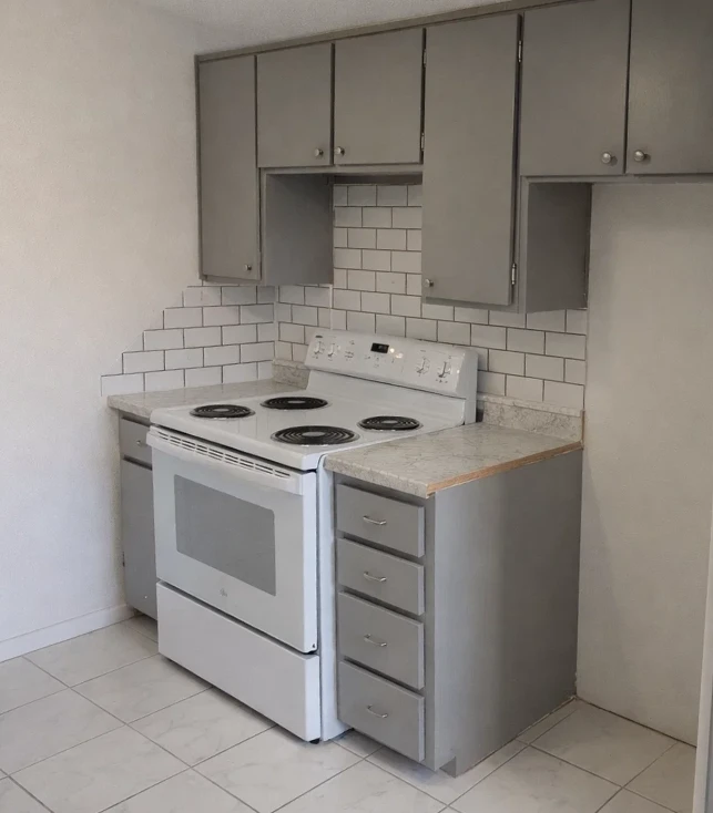 White electric range and oven surrounded by grey cabinets and subway tile at Parkview apartments in El Reno.