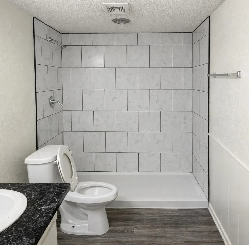 Modern bathroom with walk-in shower and marble-style tile at La Villa Elms Apartments in El Reno.